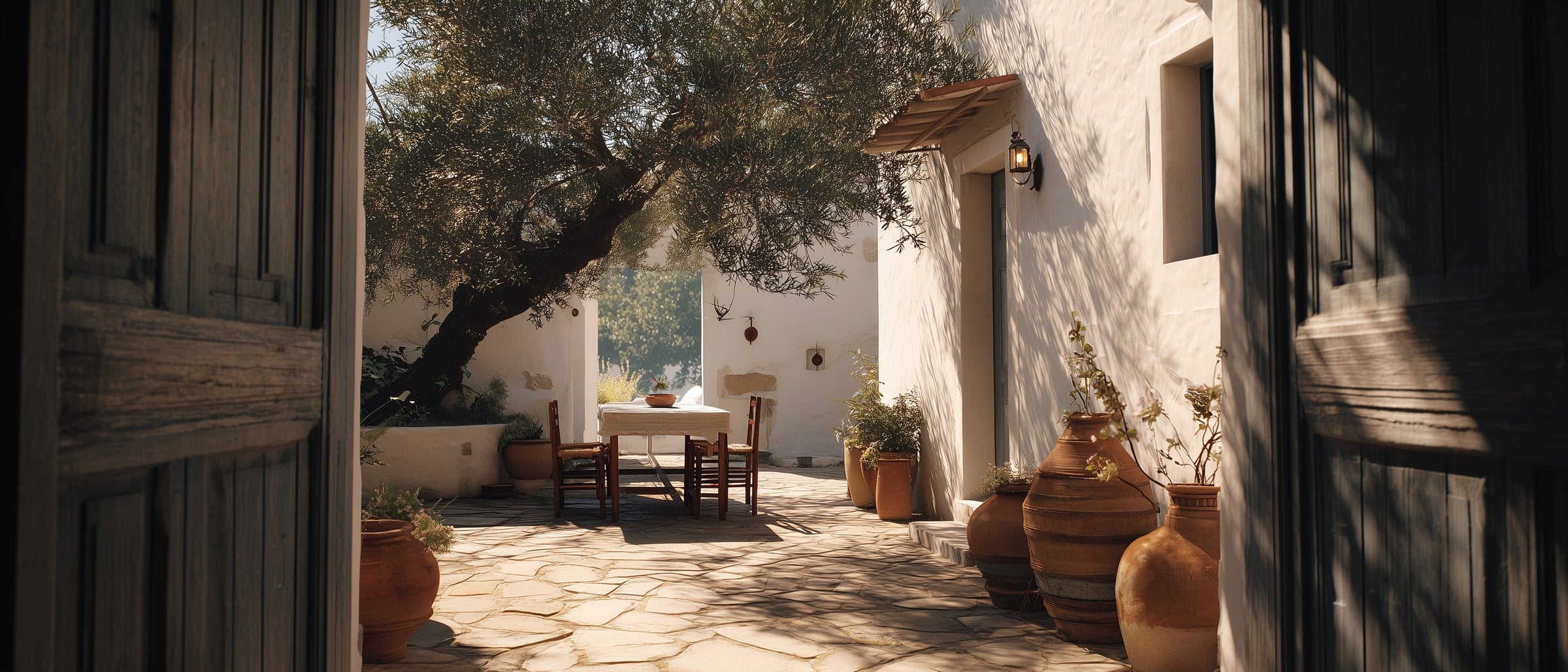 A table set in a Mediterranean courtyard beneath an olive tree
